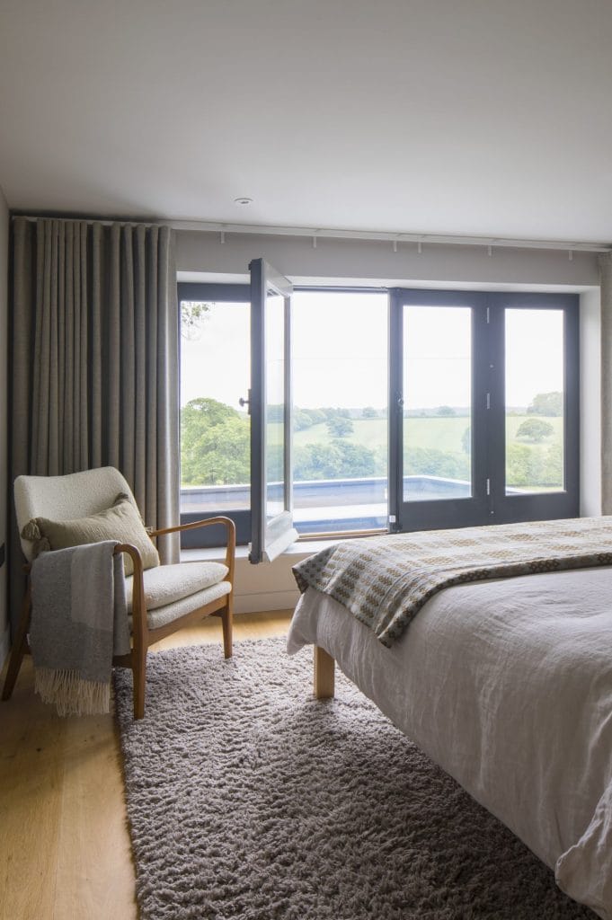 Interior of Sussex residential conversion featuring bedroom with doors to roof terrace. Stickland Wright Architecture and Interior Design