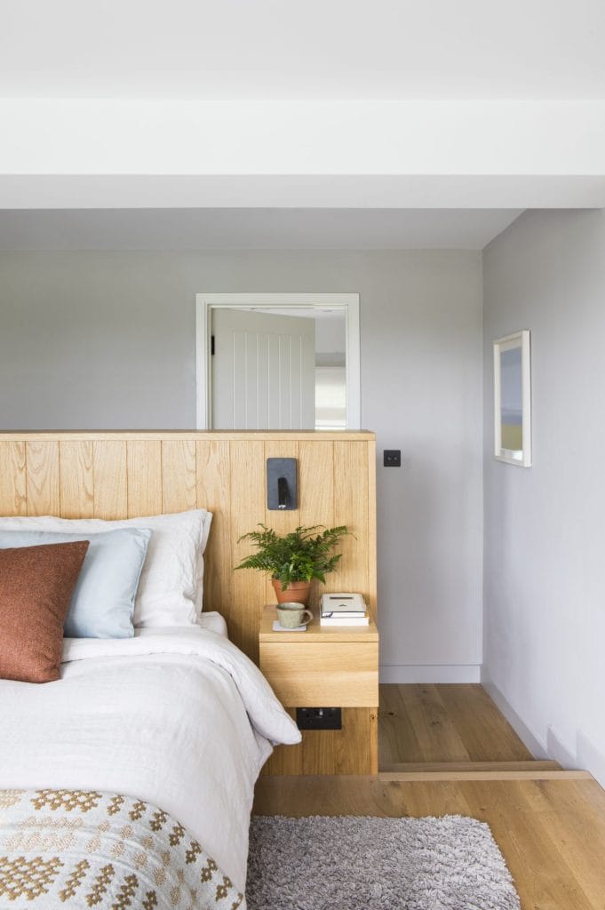 Interior of Sussex residential conversion featuring bed with bespoke oak headboard. Stickland Wright Architecture and Interior Design