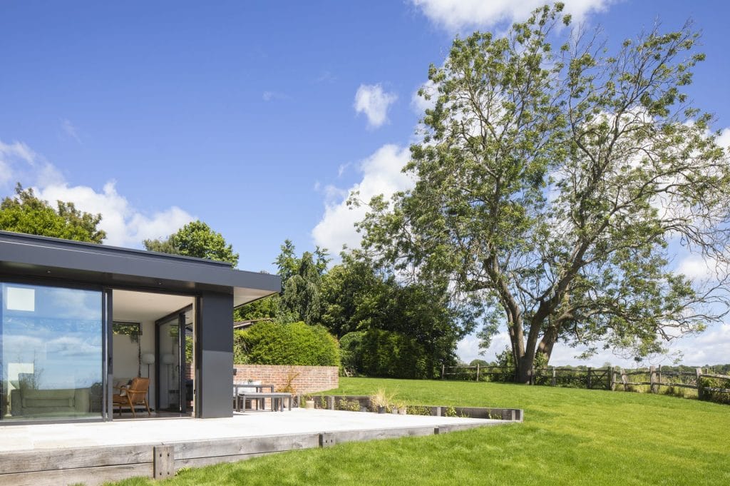 Heritage residential conversion in Sussex, featuring brick house, patio, and lawn. Stickland Wright Architecture and Interior Design