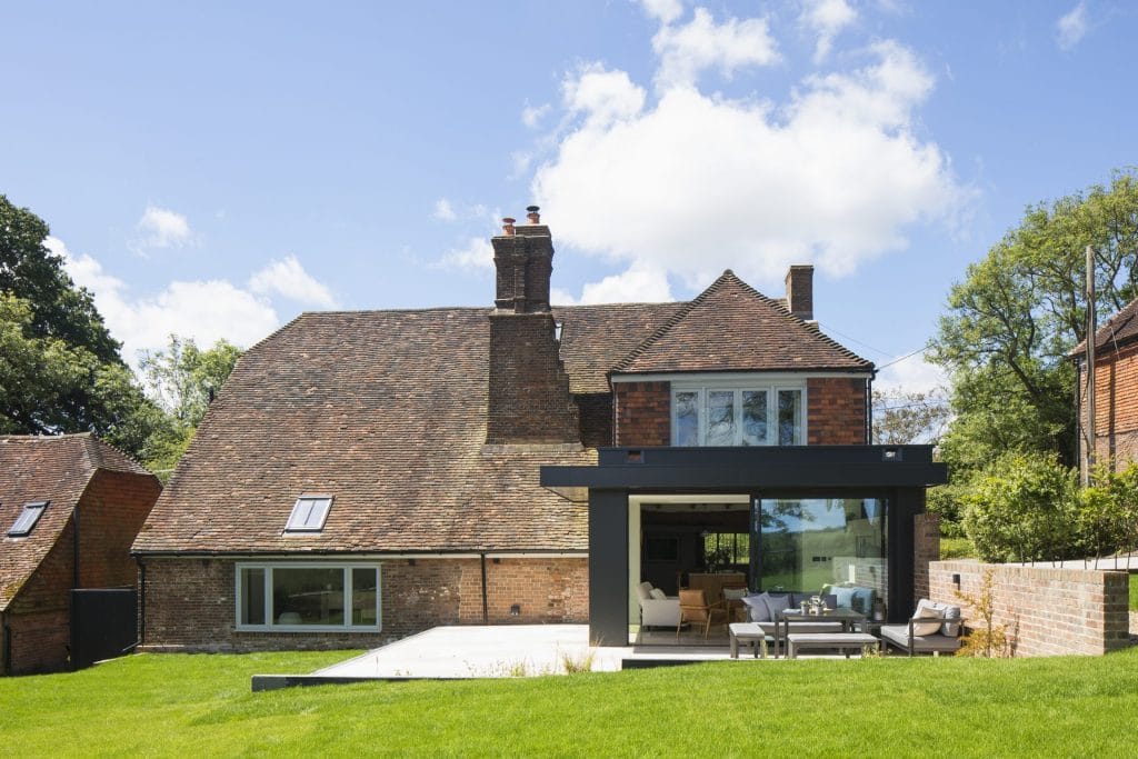 Heritage residential conversion in Sussex, featuring brick house, patio, and lawn. Stickland Wright Architecture and Interior Design