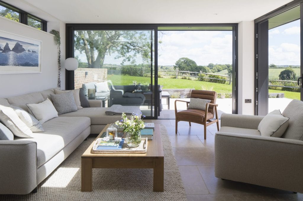 A well-designed living room featuring a comfortable couch, coffee table, and a picturesque window. Stickland Wright Architecture and Interior Design