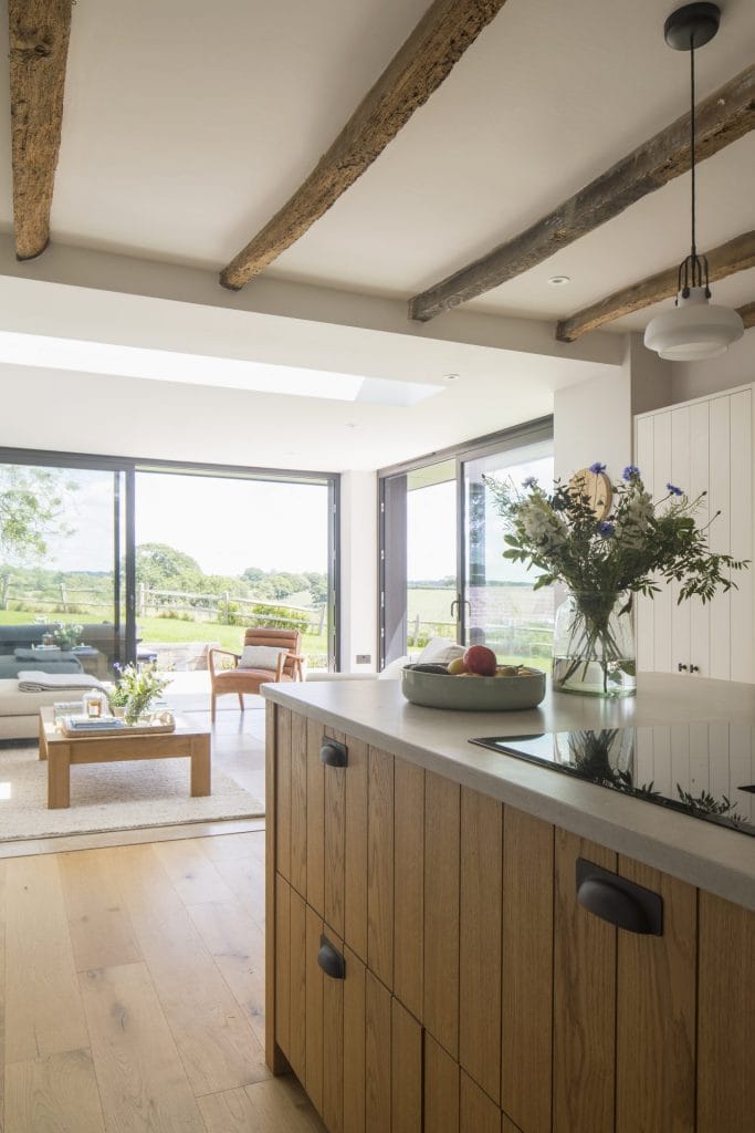 Interior of Sussex residential conversion featuring kitchen with islane table and chairs. Stickland Wright Architecture and Interior Design