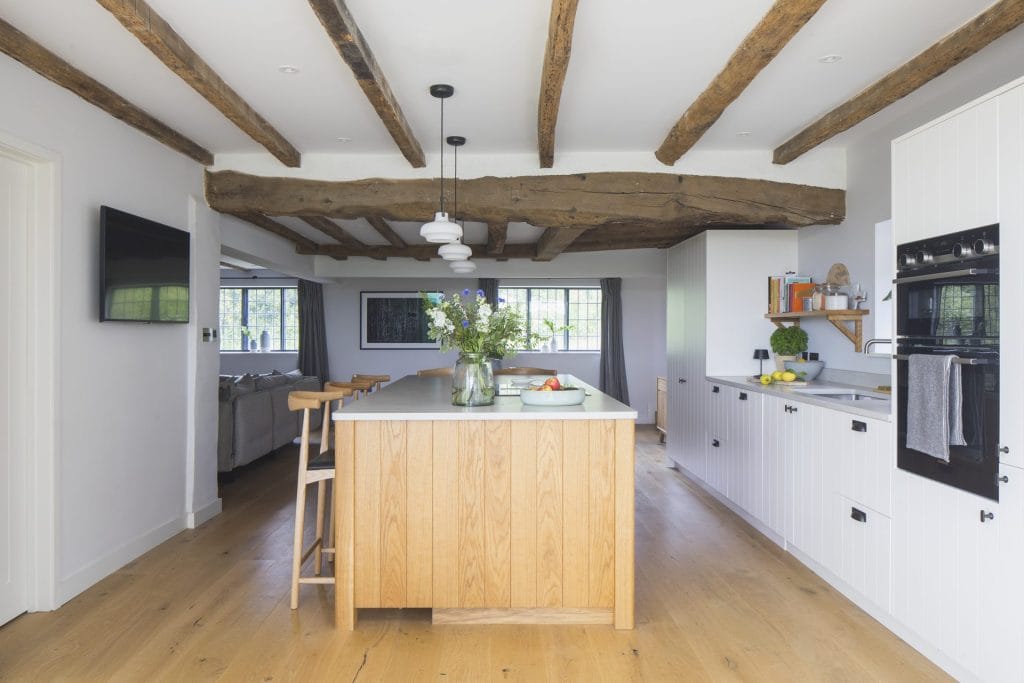 Interior of Sussex residential conversion featuring kitchen with islane table and chairs. Stickland Wright Architecture and Interior Design