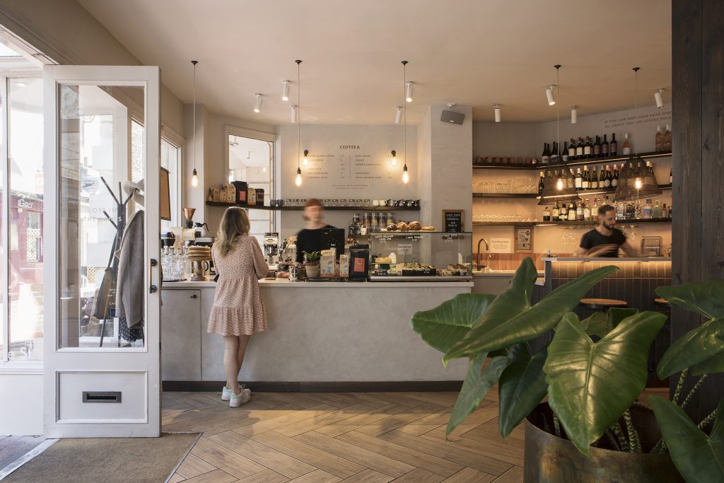 View of a cafe serving counter. A women in a pink dress is ordering from the waitress. Stickland Wright Architects and Interior Design, Brighton & Hove
